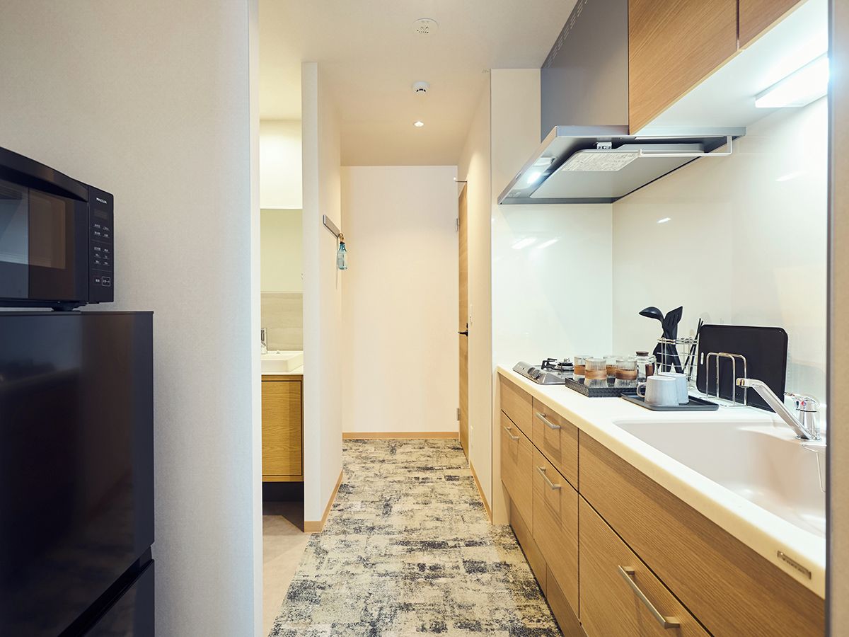 A modern kitchen with a refrigerator, microwave, and a countertop with a sink and various items.