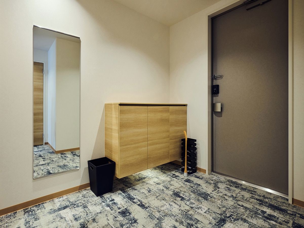 Ein Flur mit einem Holzschrank, einem Spiegel, einer Tür und einem gemusterten Teppich.