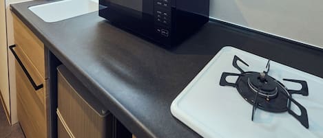 Une cuisine équipée d’un four à micro-ondes et d’une cuisinière à gaz.