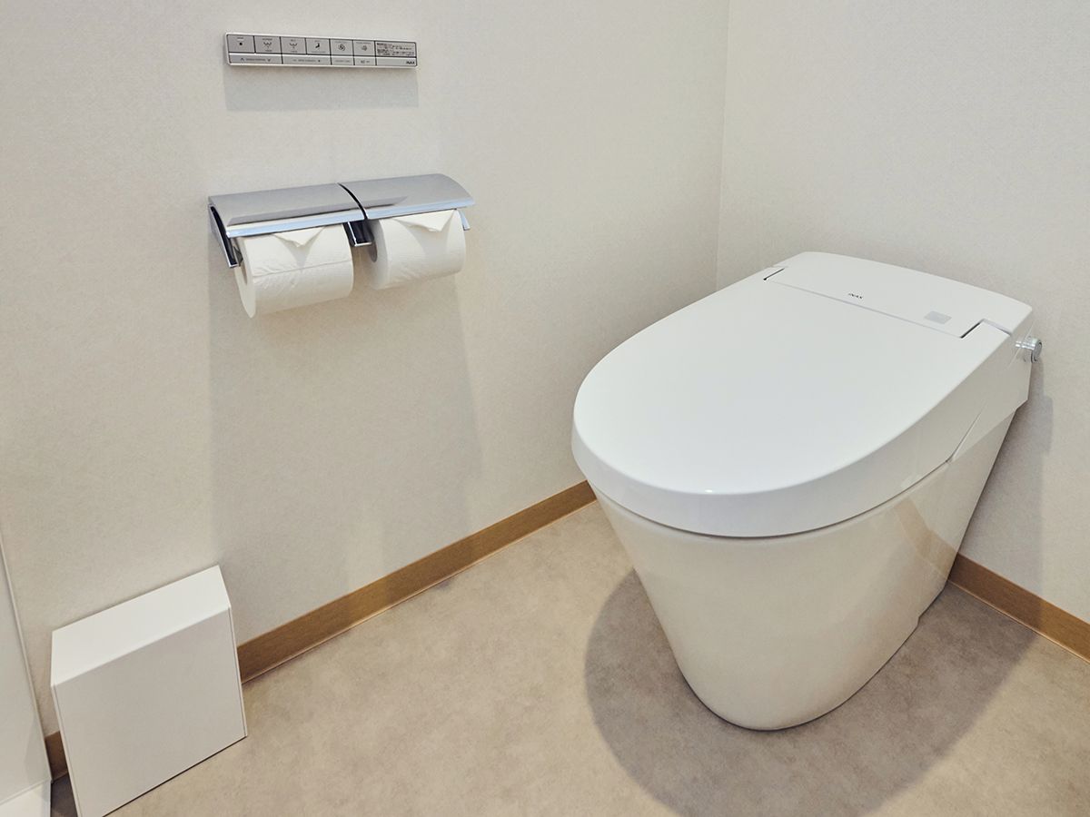 A standard bathroom with a toilet, a paper towel dispenser, and a trash bin.