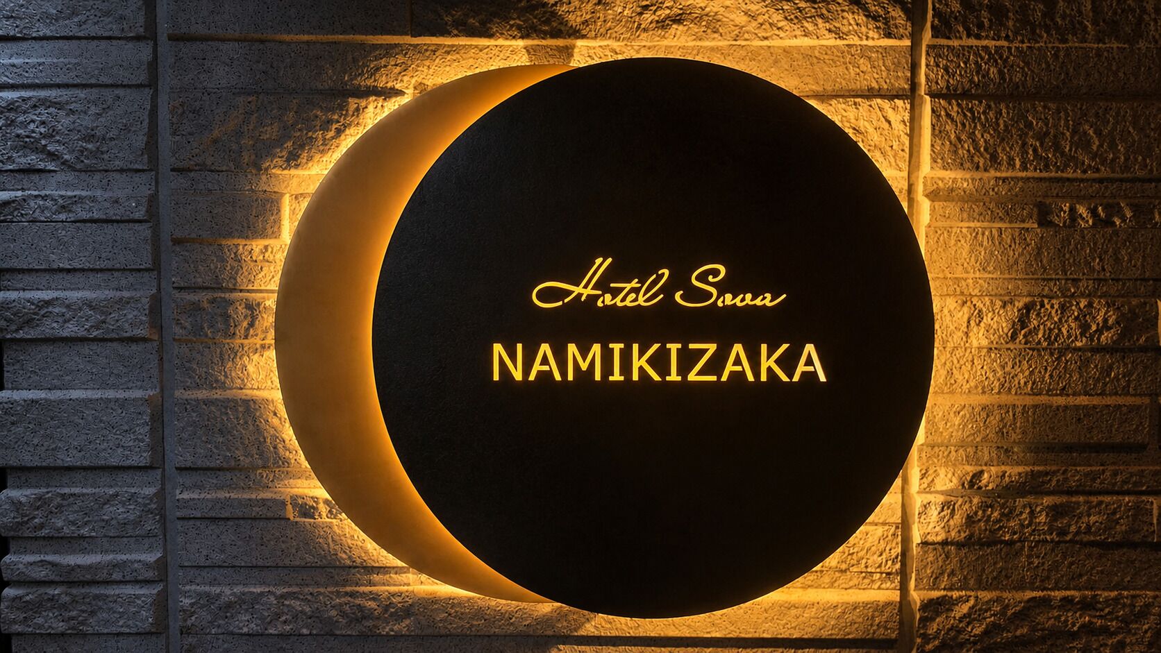 A circular sign with 'Hotel Sowa NAMIKIZAKA' text, mounted on a stone wall.