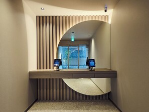 A modern bathroom with a vanity, two monitors, and a view of the outdoors.