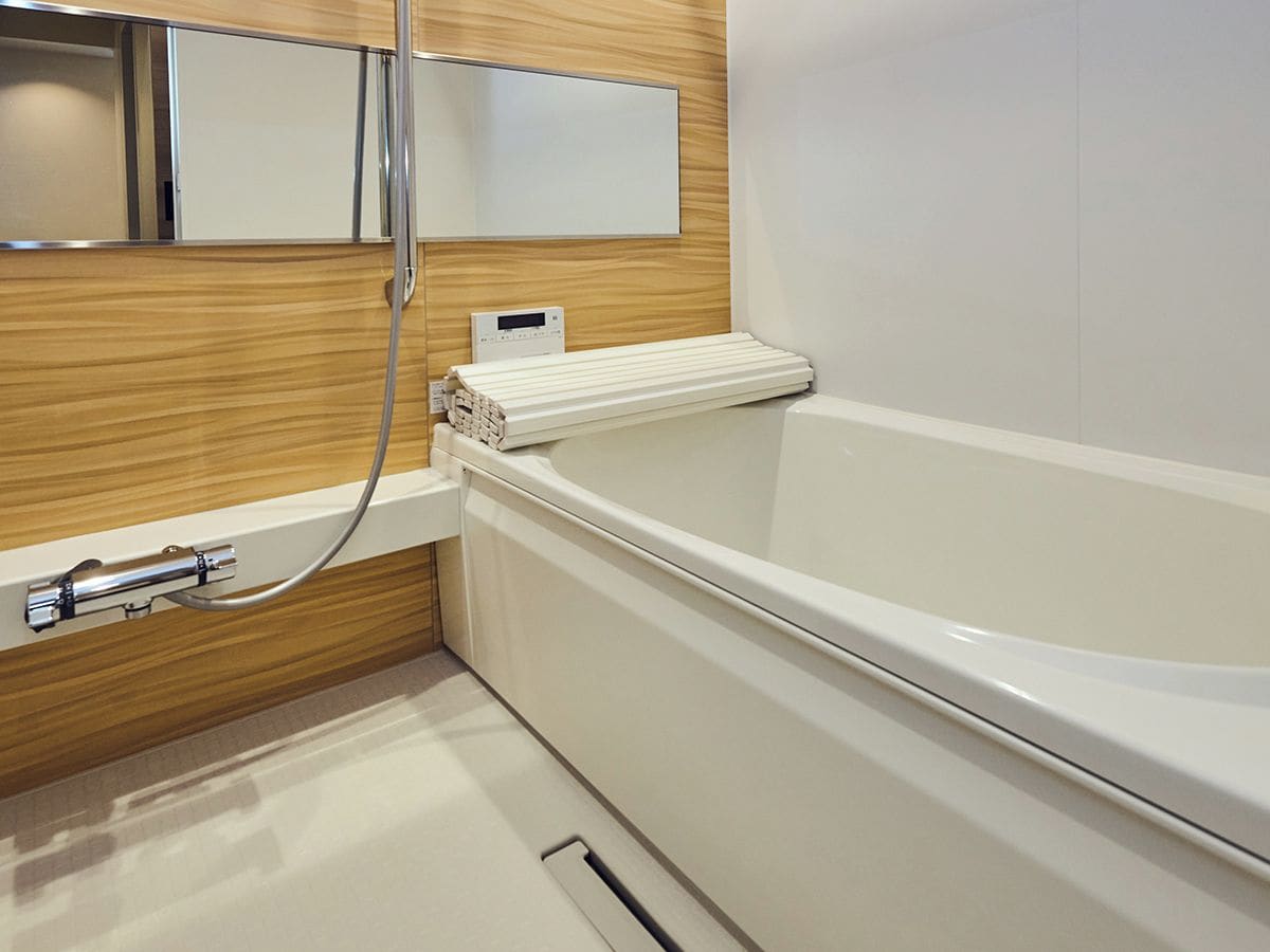 A modern bathroom with a white bathtub, a wooden vanity, and a mirror above the sink.
