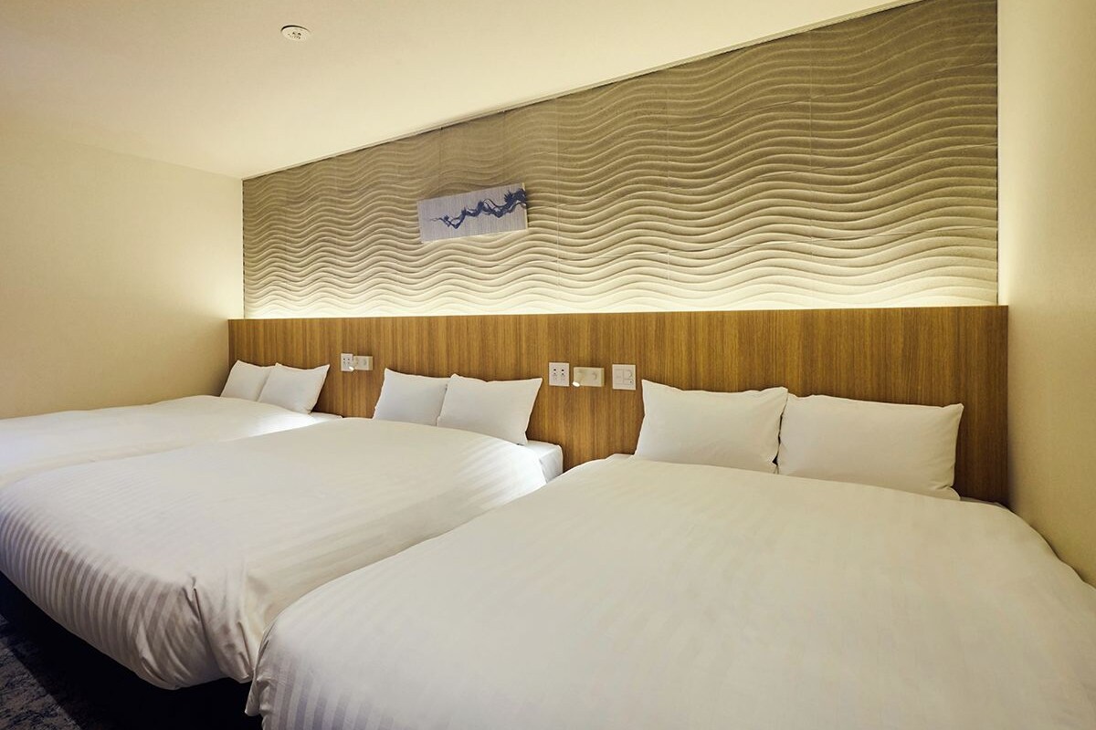 A hotel room with two beds, a wooden headboard, and a wall-mounted artwork.