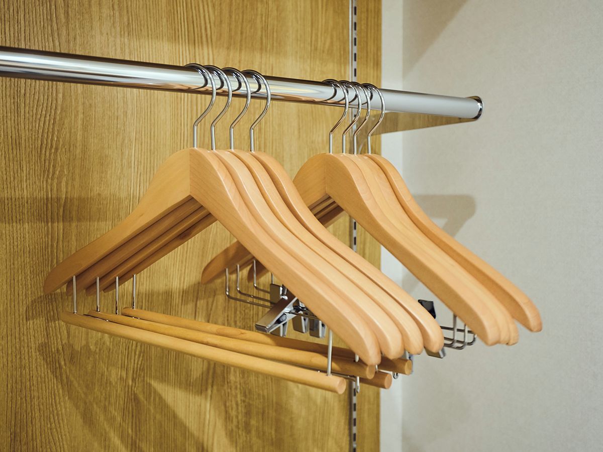 A wooden hanger rack with multiple hangers against a wooden door.