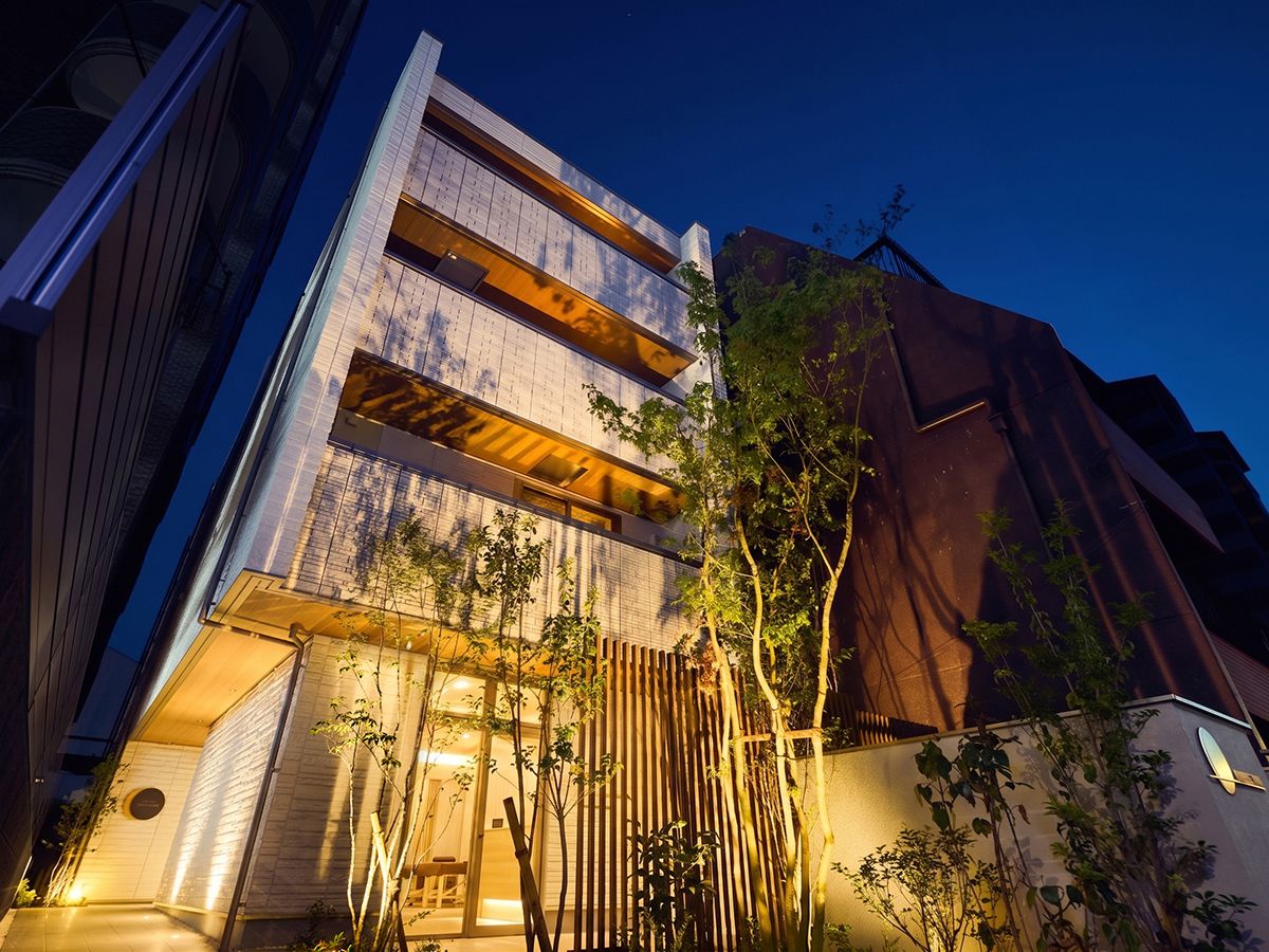 Een modern gebouw met een platte gevel, grote ramen en een houten omheining met beplanting.