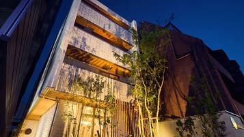 Een modern gebouw met een platte gevel, grote ramen en een houten omheining met beplanting.