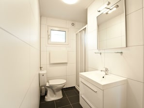 Ein modernes Badezimmer mit Toilette, Waschbecken und Spiegel.