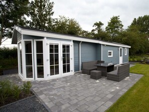 Ein modernes Haus mit Terrasse, einer Glastür und einem kleinen Garten.