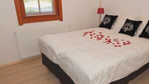 Une chambre à coucher avec un lit, une fenêtre avec des stores, un radiateur et une lampe de chevet.