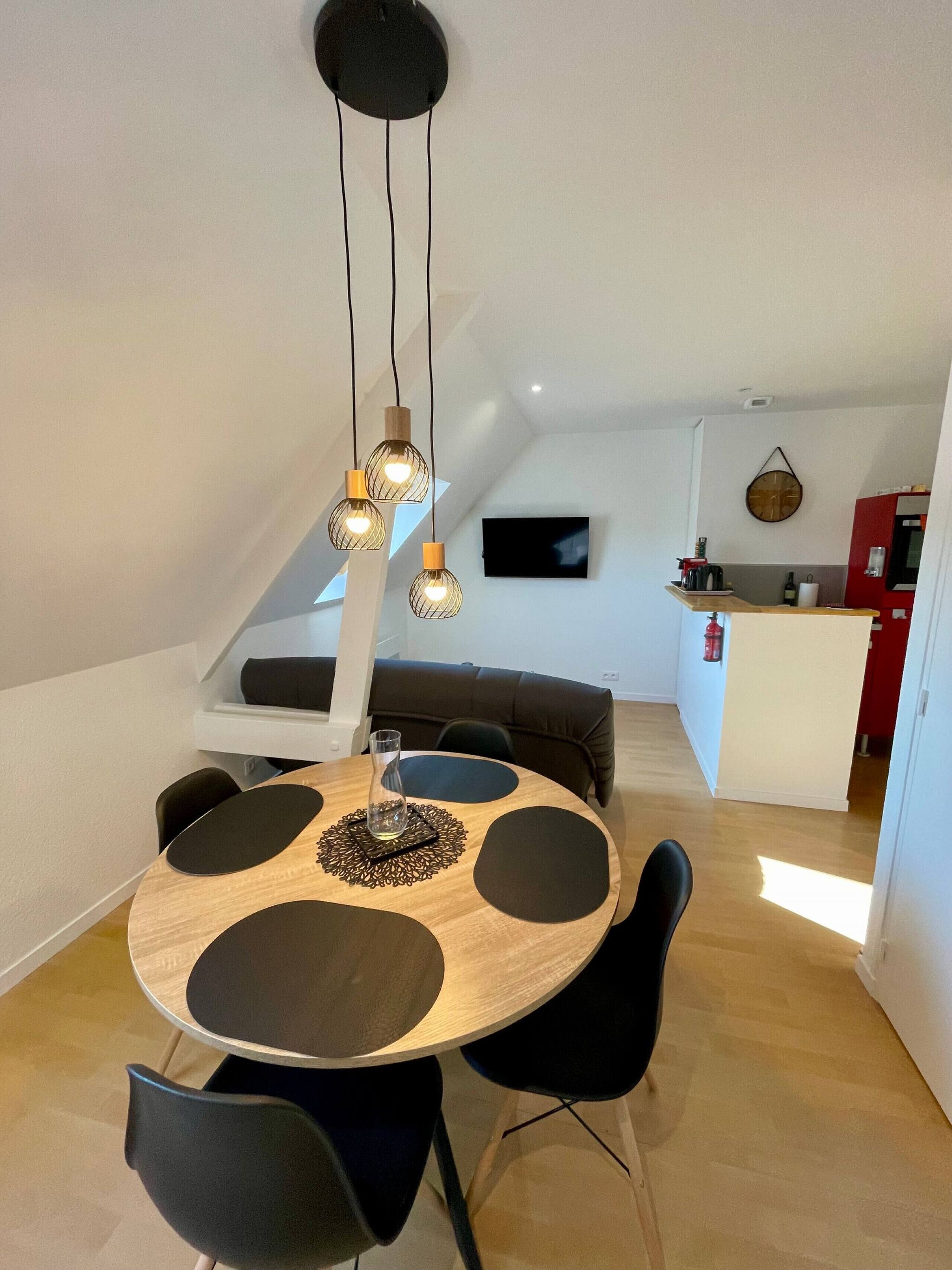 Een eetruimte met een ronde tafel, zwarte stoelen en hanglampen.