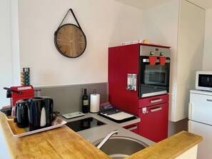 A compact kitchen with a coffee machine, toaster, wine bottle, paper towel holder, and a microwave. - AppartCosy 23 Central Studio (Vitré)