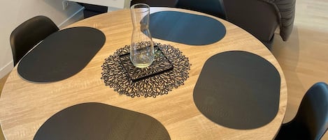 Un coin repas avec une table ronde, des chaises noires et un vase en verre.