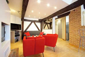 Ein modernes Wohnzimmer mit Kamin, roten Möbeln und freiliegenden Holzbalken.