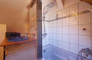 Ein modernes Badezimmer mit Duschkabine aus Glas, einer Badewanne und einem Waschtisch.