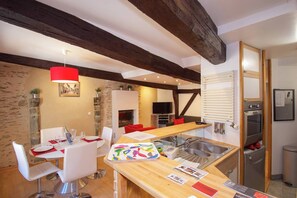 Een moderne keuken met een houten plafond, een eethoek met witte stoelen en een rode hanglamp.