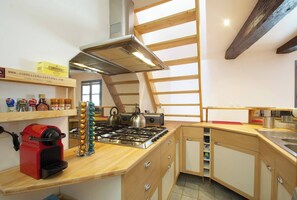 Een keuken met een gasfornuis, een rode apparate en een houten plafond.