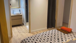 A bedroom with a bed, a bathroom with a sink and mirror, and a closet.
