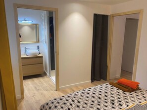 Ein Schlafzimmer mit Bett, ein Badezimmer mit Waschbecken und Spiegel sowie ein Kleiderschrank.