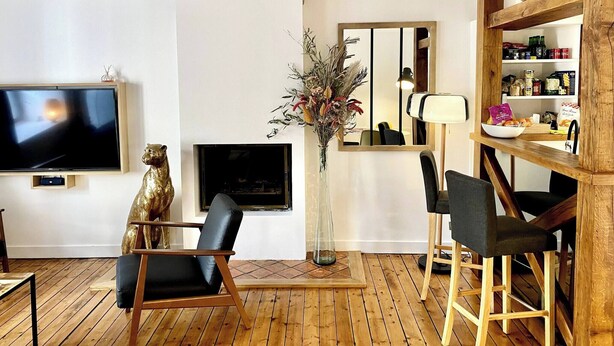 A living room with a TV, a decorative bear statue, a vase with dried flowers, a mirror, and a wooden bookshelf.