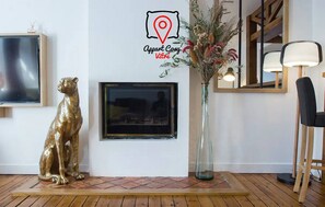 Een kamer met een ingelijste televisie, een decoratief gouden beeldje, een vaas met gedroogde bloemen en een spiegel.