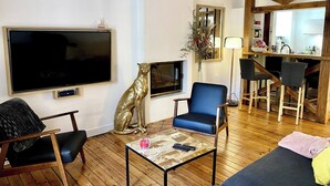A living room with a TV, a sofa, a coffee table, and a fireplace.