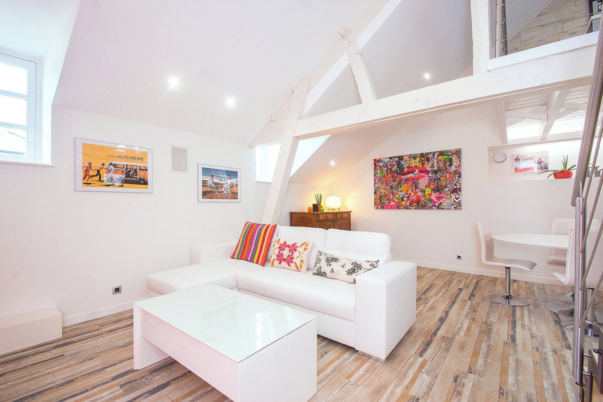 Un salon moderne avec un canapé blanc, une table basse et des œuvres d’art accrochées aux murs.