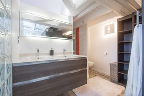 Een moderne badkamer met een dubbele wastafel, een grote spiegel en een douche.