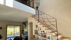 A spacious living area with a staircase leading to an upper level, a large window, and a chandelier. - Riverside House with Jacuzzi (Vitré)