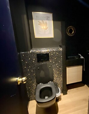 A bathroom with a toilet, a sink, a mirror, and a wall-mounted sign reading 'BLOSSOM'. - AppartCosy 15 ArtDéco (Vitré)