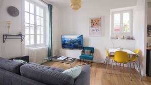 A modern living room with a sofa, TV, and dining area with chairs. - AppartCosy 09 for 4 people in a charming house (Vitré)