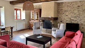 A living room with a stone fireplace, a television, and red sofas.