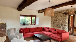 A living room with a red sectional sofa, a grey armchair, a black coffee table, a wicker pendant light, and a stone wall.