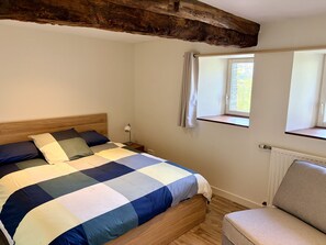 Une chambre à coucher avec un lit en bois, une table de chevet, une chaise et une fenêtre donnant sur un beau paysage.