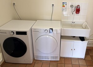 Two front-loading washing machines, a white sink, and a red fire extinguisher mounted on the wall.