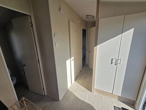 A hallway with a wardrobe, a door leading to a bathroom, and a light switch on the wall. - Caravan Stacey 3 BEd (Rhyl)