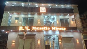 Un edificio con un letrero que dice 'R.K. Majestic Mirage' y 'Habitaciones con/sin aire acondicionado'.