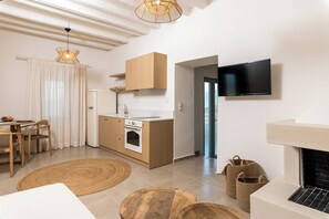 A modern kitchen with wooden cabinets, a built-in oven, and a flat-screen TV mounted on the wall. - Amvikas: Ampelos Suite-Sitia (Sarantapichos)