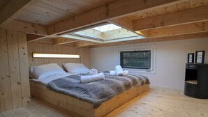 A wooden bedroom with a skylight, a bed with white linens, and a small bedside table. - Holiday Home in Velsen-zuid With Terrace (Velsen-Zuid)
