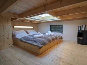 A wooden bedroom with a skylight, a bed with white linens, and a small bedside table. - Holiday Home in Velsen-zuid With Terrace (Velsen-Zuid)