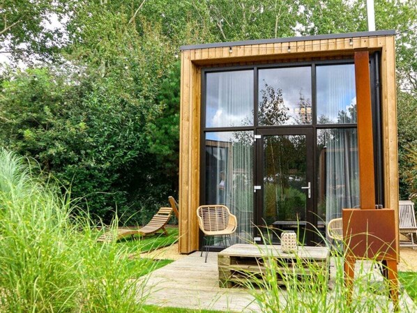 A modern, wooden-framed structure with large glass windows, outdoor seating, and a garden setting. - Holiday Home in Velsen-zuid With Terrace (Velsen-Zuid)