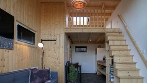 A wooden interior with a sofa, a small table, a staircase, and a view of the outside. - Holiday Home in Velsen-zuid With Terrace (Velsen-Zuid)