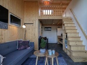 A wooden interior with a sofa, a small table, a staircase, and a view of the outside. - Holiday Home in Velsen-zuid With Terrace (Velsen-Zuid)