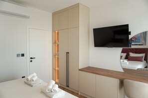 A hotel room with a bed, a TV, a wardrobe, and a desk.