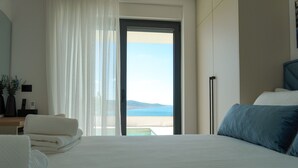 A hotel room with a bed, a desk with a lamp, a view of the sea, and a sliding door. - Villa Bella Vista with heated pool (Rovanjska)