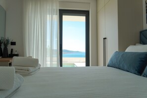 Une chambre d’hôtel avec un lit, un bureau avec une lampe, une vue sur la mer et une porte coulissante.