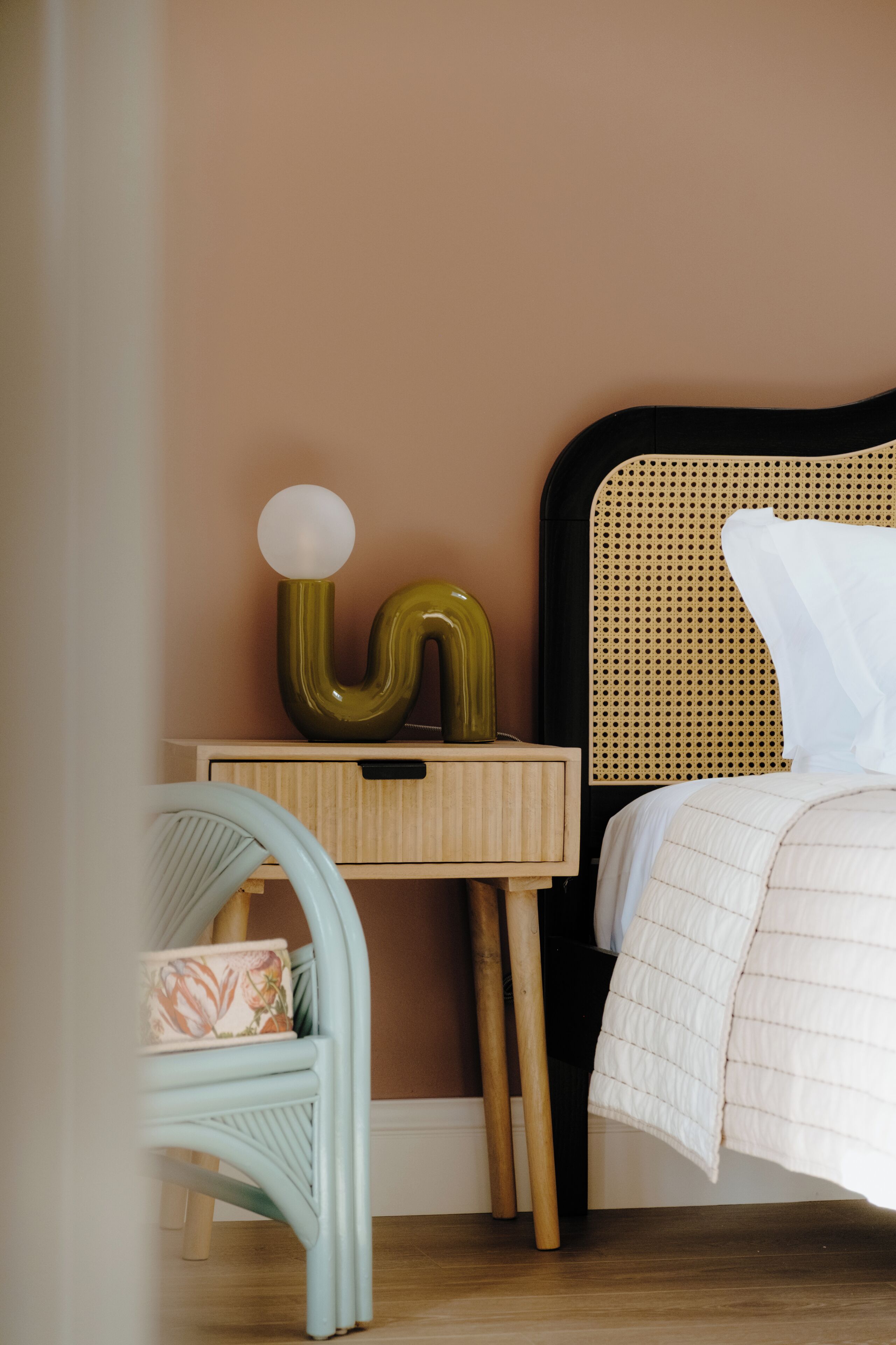 A bedroom with a bed, a nightstand, a lamp, and a chair.