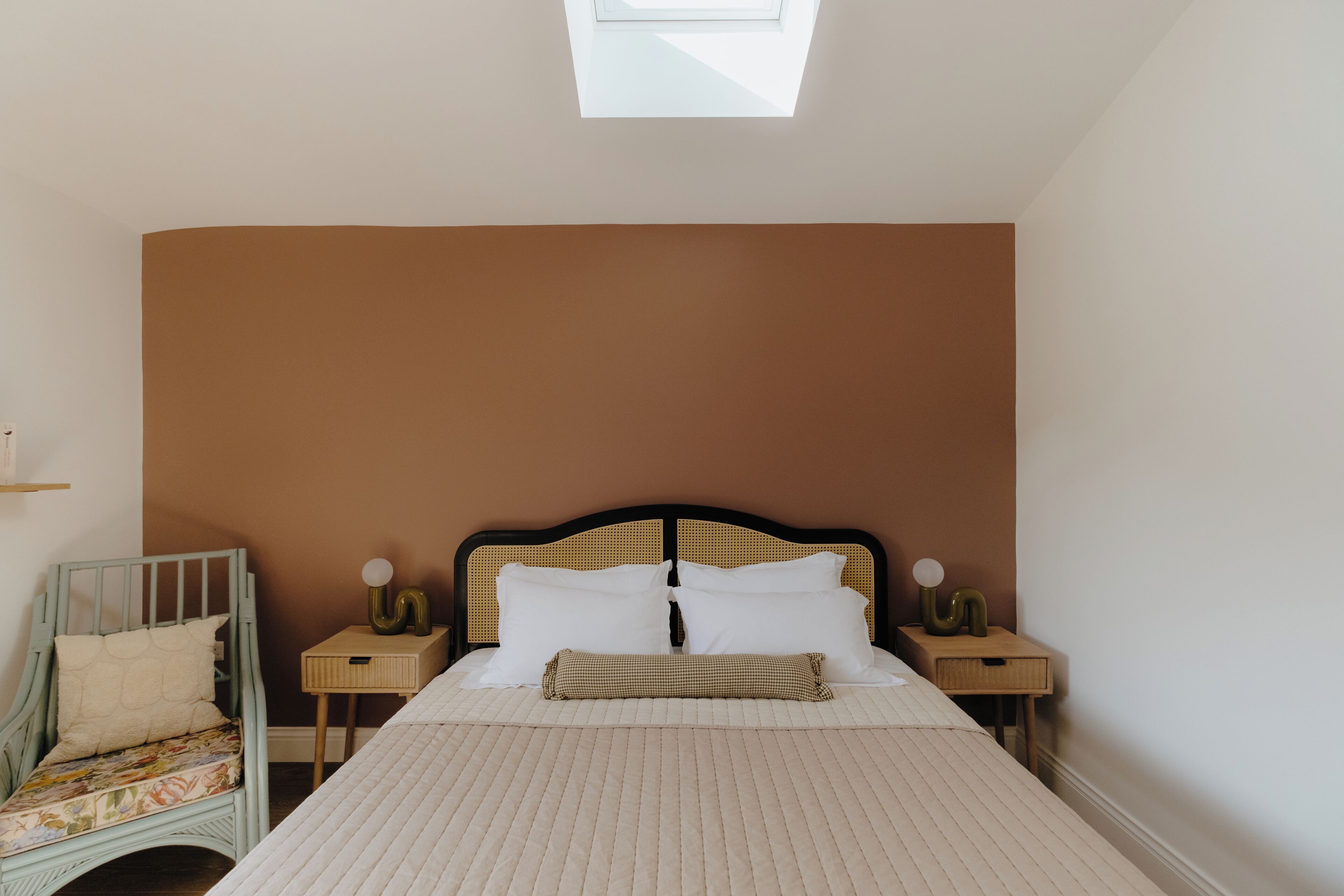 Une chambre à coucher avec un lit, une table de chevet, une chaise et une lucarne.