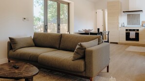 Ein modernes Wohnzimmer mit einer Couch, einem Couchtisch und einer Küche im Hintergrund.