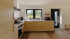 Eine moderne Küche mit Holzschränken, einem großen Fenster und einer eingebauten Mikrowelle.